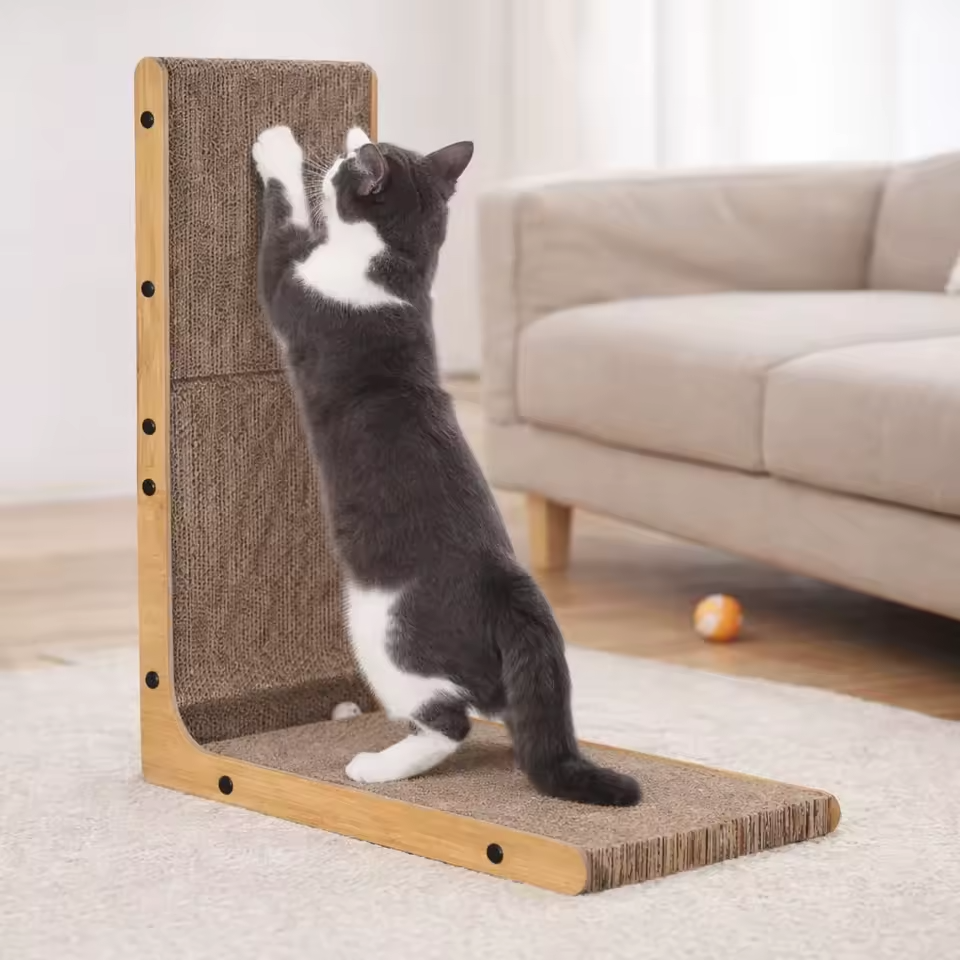 Black and white cat stretching and scratching L-shaped cardboard scratcher – lifestyle photo
